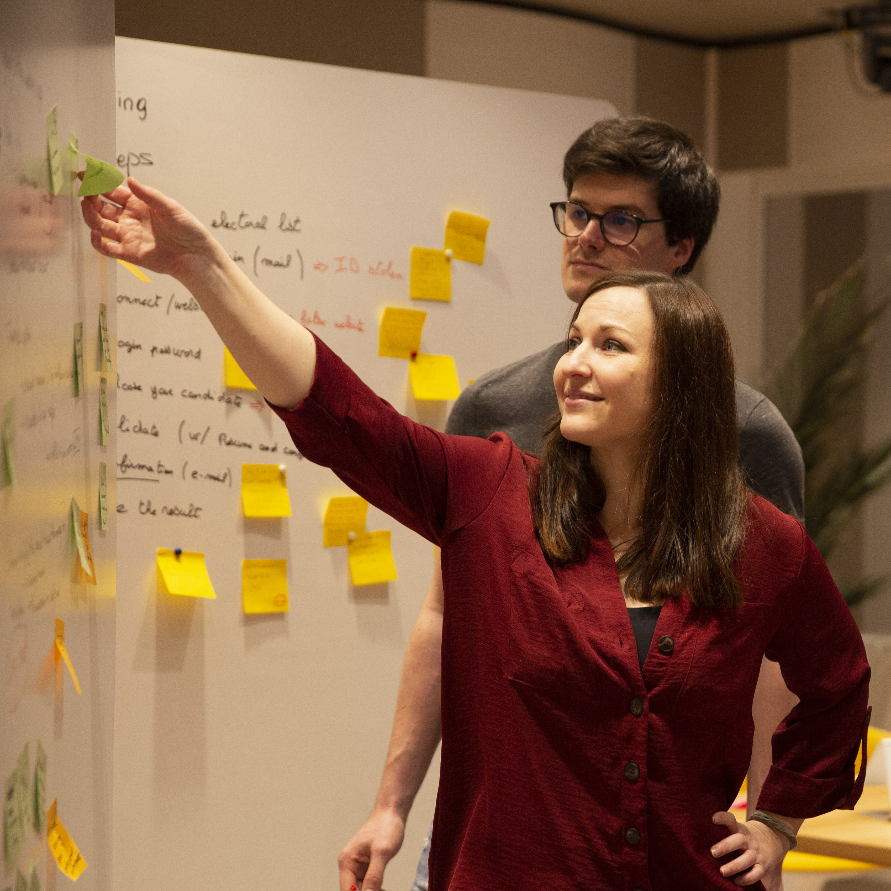 Two team members working on a whiteboard with post-its